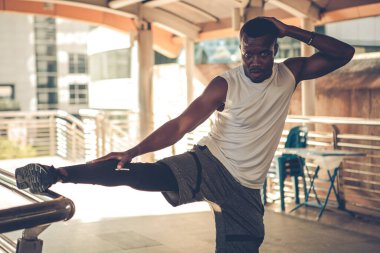 Fit runner African American young man doing stretching in the city. Handsome young man exercise outdoors.