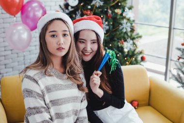 Two young Asian women with celebrate Christmas together at the home.