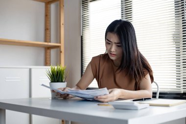Genç Asyalı kadın, birçok kredi kartı ve fatura borçlarından dolayı stresli ve fazla kafa yoruyor. Finansal sorun kavramı. Kadınlar borçtan kurtulmanın bir yolunu buldular..