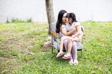 Asian mum and daughter do fun activities together on grass field in the garden at home. Happy loving family concept.
