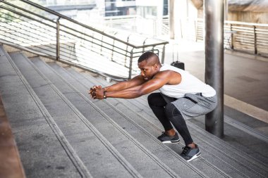 Fit runner African American young man training by upstairs at the stadium. Handsome young man exercise outdoors.