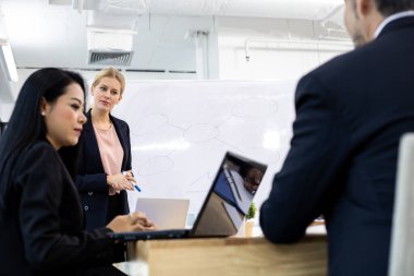 Beyaz bir kadın, toplantı odasında bir ekip kurmayı planladıkları için ekiptekilere bilgi veriyor. İş görüşmeleri konsepti.