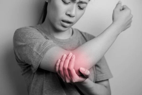 Women with pain in elbow. Acute pain in a elbow. Young woman holds on to elbow.