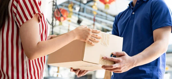 Woman receives a package from an express delivery worker in front of the house.