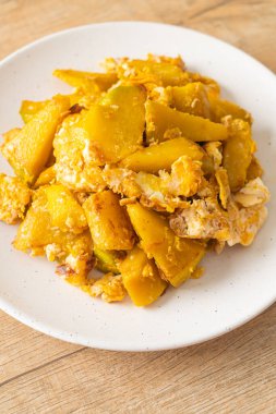 Beyaz tabakta yumurtalı kızarmış balkabağı.