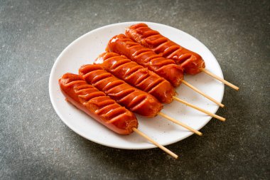 Beyaz tabakta kızarmış sosis şişi.