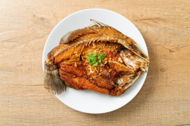 Tabakta sarımsaklı kızarmış deniz levreği balığı.