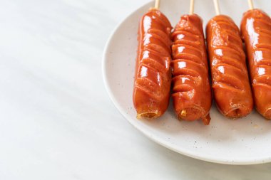 Beyaz tabakta kızarmış sosis şişi.