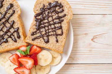 Kahvaltıda taze muz, çilek ve çikolatalı tam buğday ekmeği.