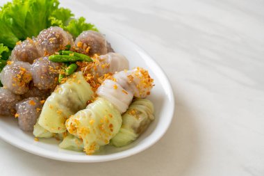 Şeffaf toplara Saku Sai Moo ya da Buharlı Tapioca Köfte Topları ve (Kow Griep Pag Mor) Domuz Buharlı Pirinç Paketleri ya da Haşlanmış Pirinç Kabuklu Mantı denir.