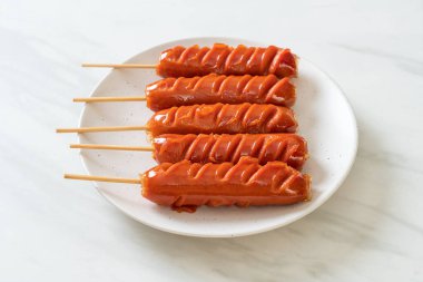 Beyaz tabakta kızarmış sosis şişi.