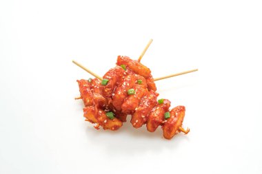 Kızarmış Kore pirinç keki (Tteokbokki) beyaz arka planda izole edilmiş baharatlı sosla şişlenmiş.