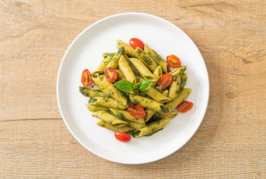 Pesto soslu ve domatesli makarna. Vejetaryen ve vejetaryen yemek tarzı.