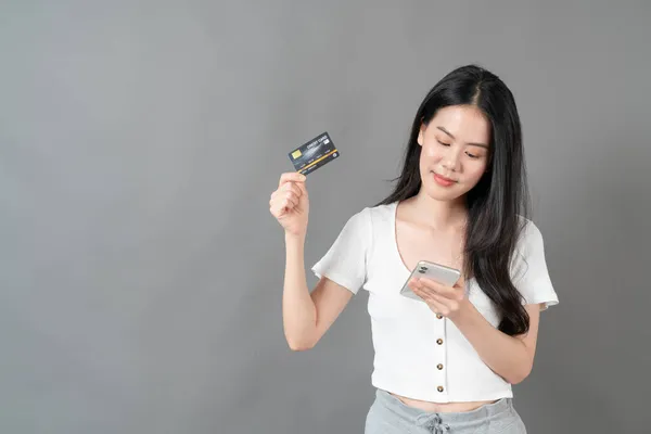 使用手持信用卡手机的年轻亚洲女人 网上购物的概念 — 图库照片