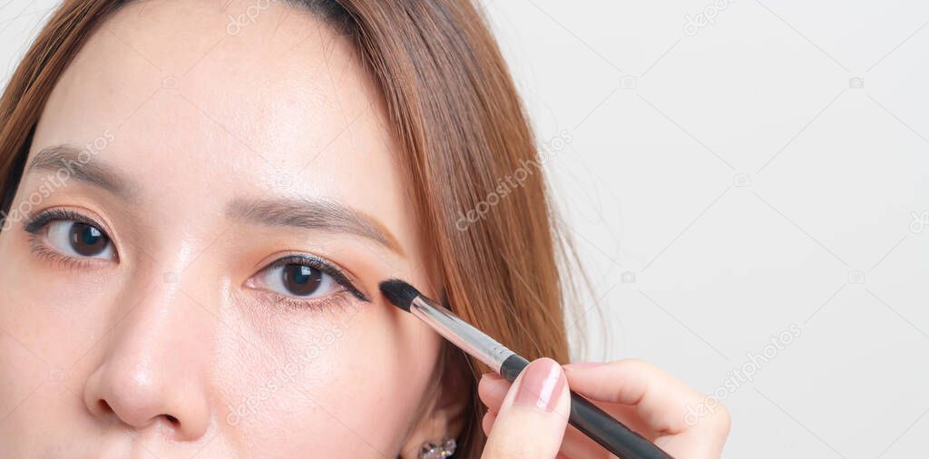 portrait beautiful Asian woman with makeup eye brush on white background