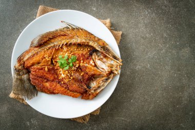 Tabakta sarımsaklı kızarmış deniz levreği balığı.