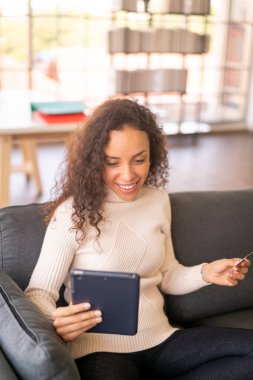 Tablet kullanan Latin bir kadın kredi kartı kullanıyor - İnternet üzerinden alışveriş kavramı