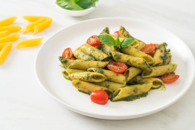 Pesto soslu ve domatesli makarna. Vejetaryen ve vejetaryen yemek tarzı.