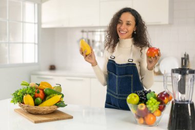 Latin kadın, vejetaryen yemeği için mutfakta meyve suyu yapıyor.