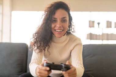 Laitin denen kadın evdeki kanepede elinde joystick ile video oyunları oynuyor.