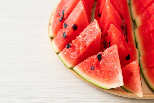 свежий арбуз, нарезанный на деревянной тарелке