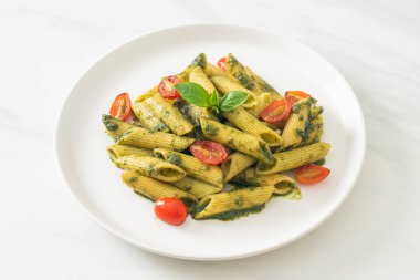 Pesto soslu ve domatesli makarna. Vejetaryen ve vejetaryen yemek tarzı.