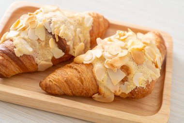 Kremalı kruvasan ve ahşap tabakta badem.
