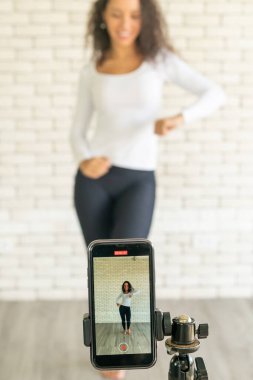 Latin kadın nüfuzlu kişi dans videosunu akıllı telefon kamerasıyla oluşturdu. Videoyu sosyal medya uygulamasına paylaşmak için.