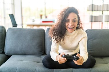 Laitin denen kadın evdeki kanepede elinde joystick ile video oyunları oynuyor.