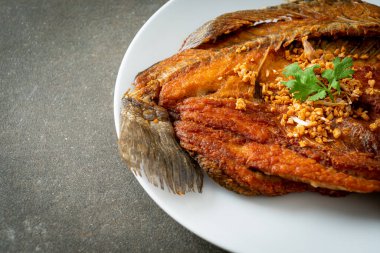 Tabakta sarımsaklı kızarmış deniz levreği balığı.