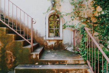 Beyaz duvarda penceresi olan eski ve klasik merdivenler.