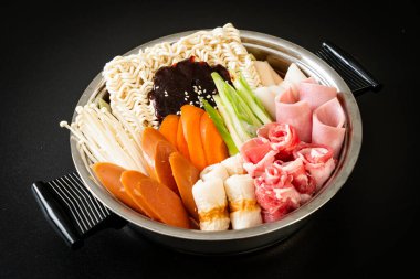 Budae Jjigae ya da Budaejjigae (ordu yahnisi ya da ordu üssü). Kimchi, konserve jambon, sosis, ramen eriştesi ve çok daha popüler Kore usulü sıcak yemek ile dolu.