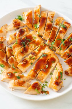 Izgara ballı tavuk göğsü. Beyaz tabakta dilimlenmiş.