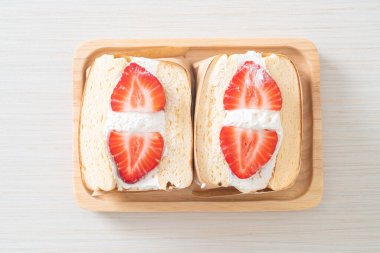 gözlemeli sandviç, çilekli taze krema, ahşap tabakta.