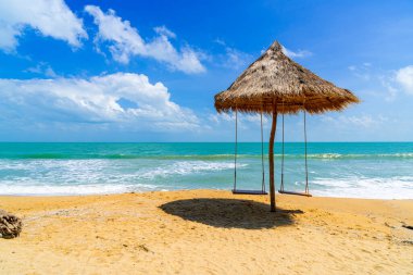 Okyanus denizi ve mavi gökyüzü arka planıyla sahilde sallan