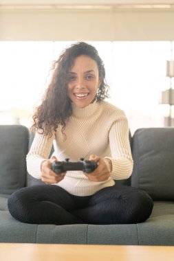 Laitin denen kadın evdeki kanepede elinde joystick ile video oyunları oynuyor.
