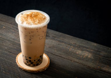 Tahta masada yanmış köpüklü ve peynirli Tayvan sütü çayı.