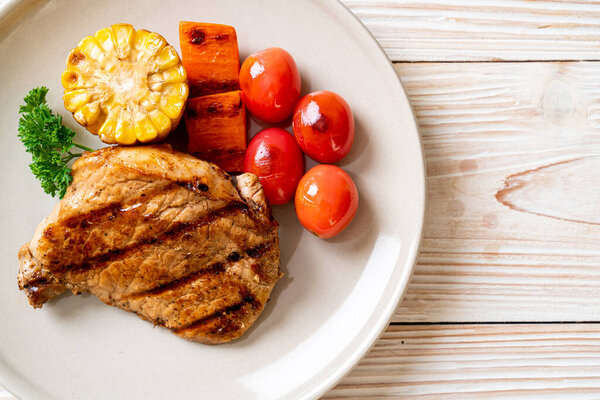 grilled and barbecue fillet pork steak with corn, carrot and tomatoes