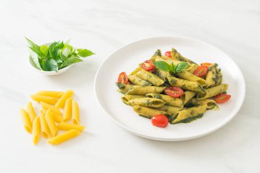 Pesto soslu ve domatesli makarna. Vejetaryen ve vejetaryen yemek tarzı.