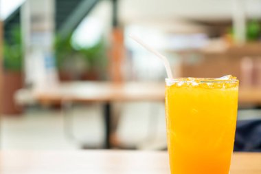 Kafe restoranındaki ahşap masada buzlu portakal suyu.