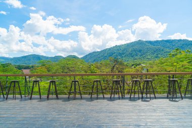 Balkonda boş bir bank ve bar taburesi var.