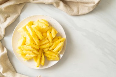 Beyaz tabakta dilimlenmiş taze ananas.