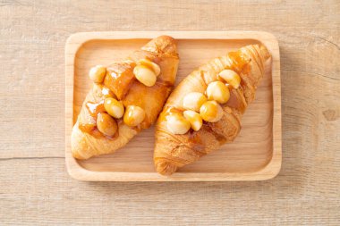 Macadamia ve ahşap tabakta karamel ile kruvasan.