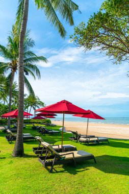 Plaj sandalyesi ve şemsiyesi okyanus sahili arka planında.