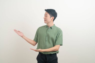 Beyaz arka planda eli işaret eden ya da sunan genç Asyalı adam portresi