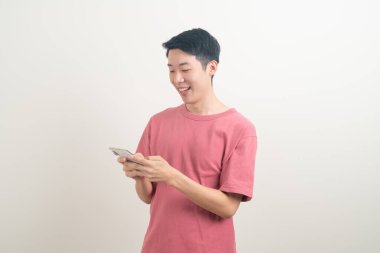 Genç Asyalı adam beyaz arka planda mutlu yüzlü akıllı telefon ve cep telefonu kullanıyor veya konuşuyor