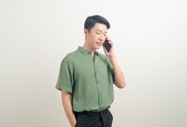 Beyaz arka planda akıllı telefon ve cep telefonu kullanan ya da konuşan genç Asyalı adam