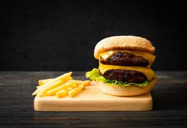 Peynirli ve patates kızartmalı hamburger veya sığır burger. Sağlıksız yemek tarzı.