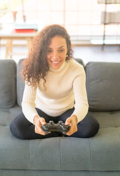 Laitin denen kadın evdeki kanepede elinde joystick ile video oyunları oynuyor.