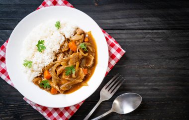 Dilimlenmiş domuz eti, havuç ve soğanlı Japon körili pilavı. Asya usulü.